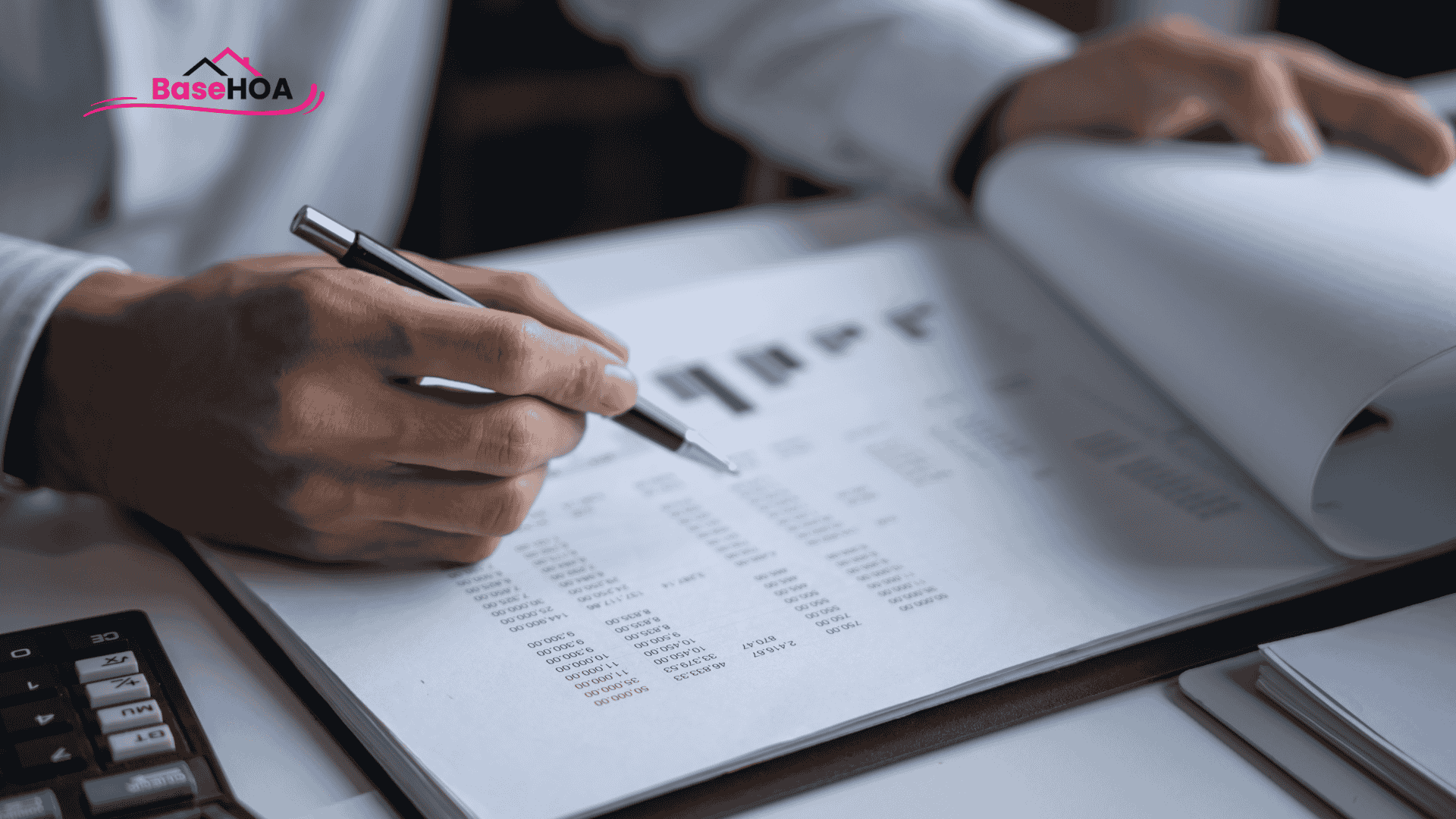Close-up of hands reviewing an HOA statement or financial documents in a binder, with a pen ready to sign or make notes.